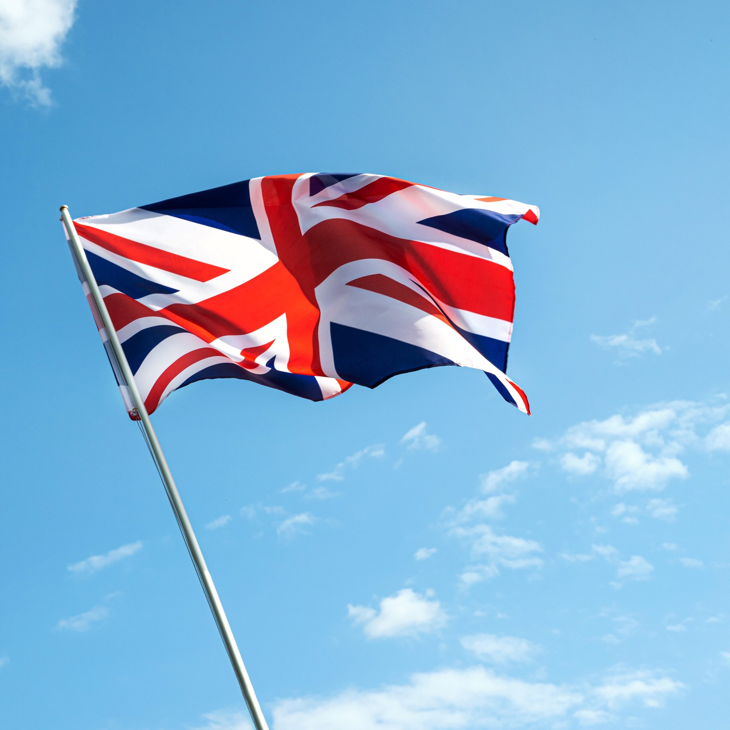 Great Britain England flag waving in the wind over blue sky